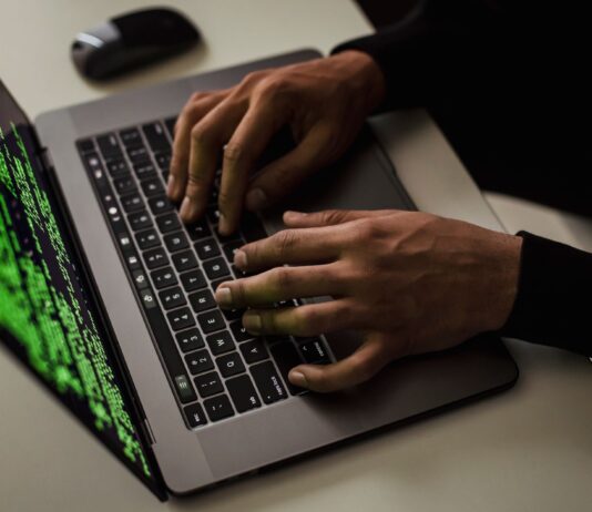 Mężczyzna piszący na netbooku z danymi na ekranie przy biurku